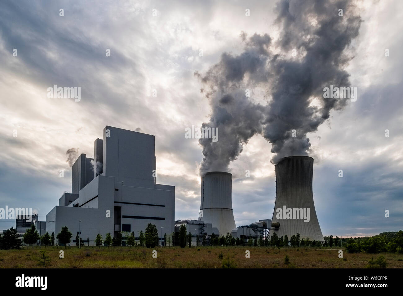 Gli edifici e la cottura a vapore delle torri di raffreddamento di un impianto alimentato a carbone nel paesaggio agricolo Foto Stock