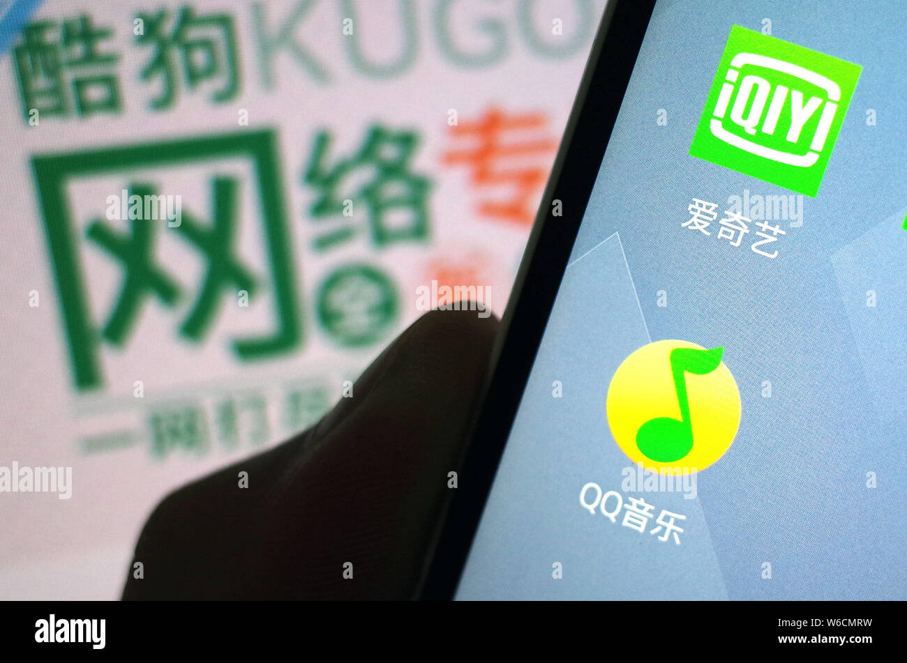 --FILE -- un telefono cellulare utente guarda le icone di QQ Musica di Tencent, inferiore e iQiyi sul suo smartphone in Ji'nan city, est della Cina di Shandong provi Foto Stock