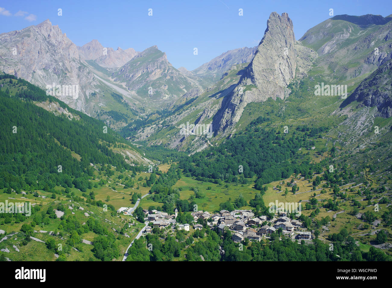 VISTA AEREA. Ultimo borgo (alt.: 1650M) dell'alta Valle Maira e della sua prominente Rocca Provenzale (alt.: 2451m). Chiappera, Piemonte, Italia. Foto Stock
