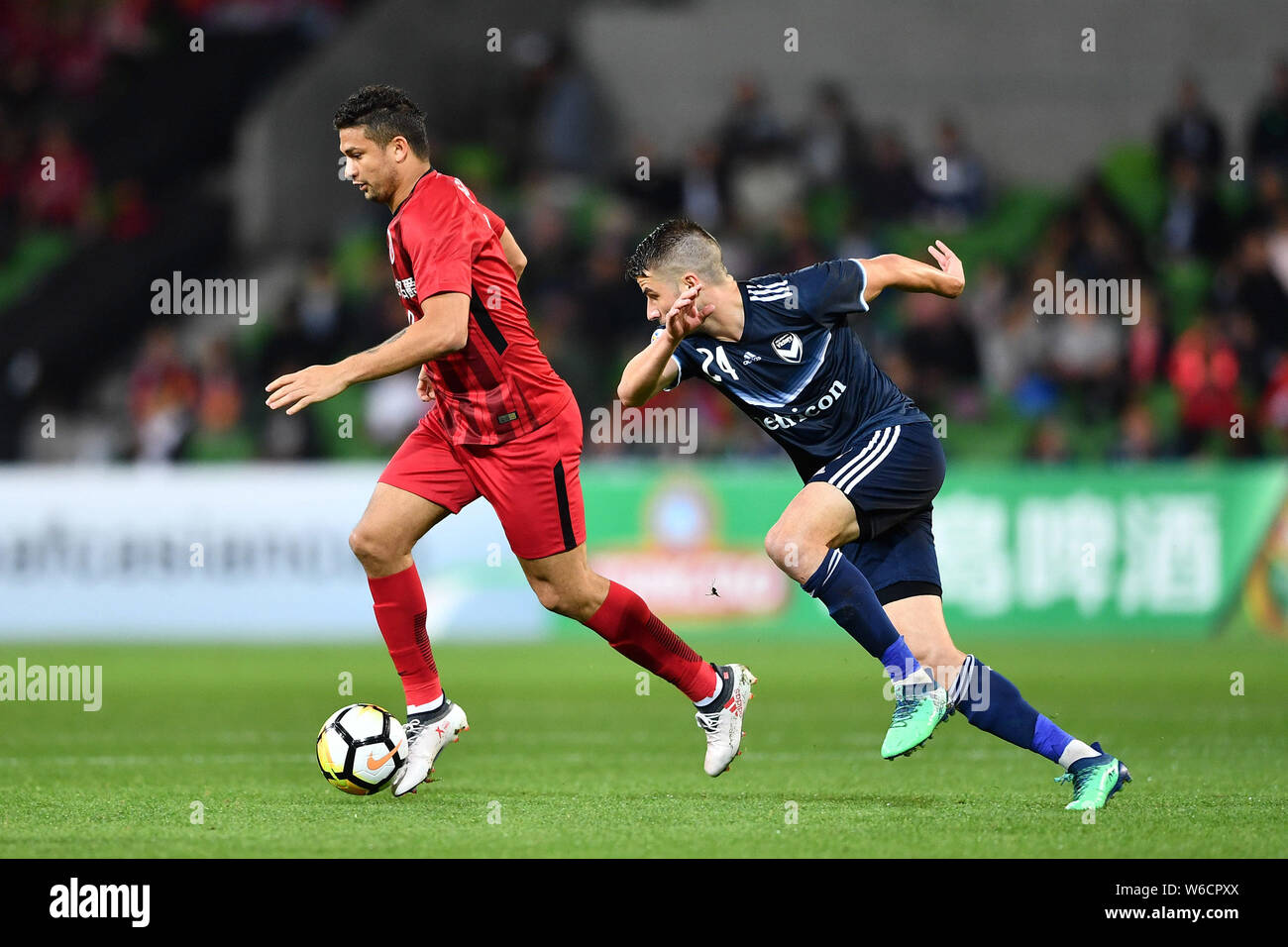 Il calcio brasiliano player Elkeson di cinese di Shanghai SIPG FC, sinistra, sfide Terry Antonis dell'Australia Melbourne vittoria FC nel loro gruppo F mat Foto Stock