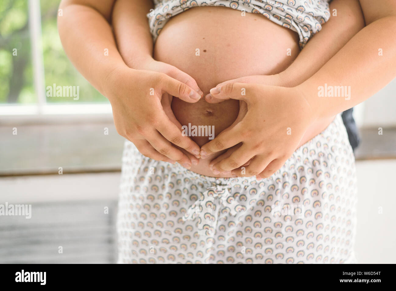 Futura Mamma e papà abbraccio il ventre di una donna in stato di gravidanza. Cuore delle mani Foto Stock