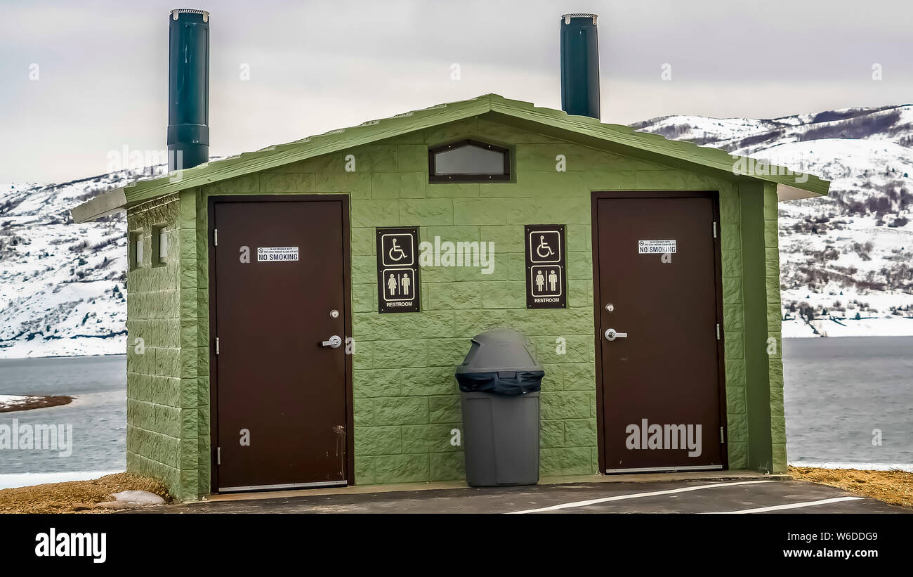 Panorama Unisex toilette pubblica contro il lago di montagna innevata e cielo molto nuvoloso in inverno Foto Stock