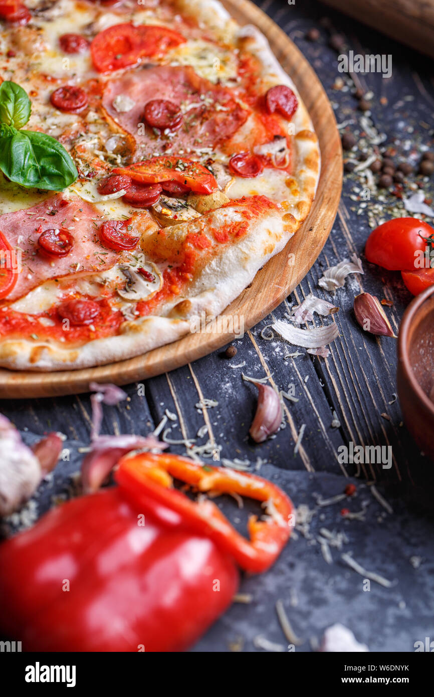 Pizza piccante con salsicce di caccia, prosciutto e funghi Foto Stock