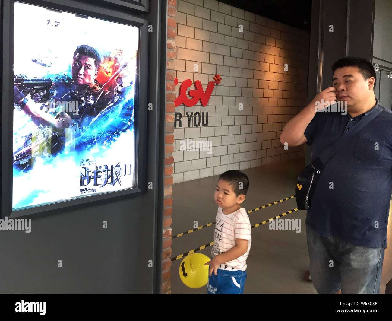 --FILE--cinesi frequentatori di film a piedi passato un poster del sistema cinese di film d'azione 'Wolf Warriors 2' visualizzato in un cinema in Cina a Shanghai, 19 agosto 2017. Foto Stock