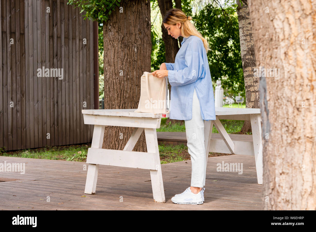 Giovane e attraente donna tenendo in cotone bianco bianco borsa di tela a parco moderno. Eco Friendly concetto .eco biodegradabili. Spazio vuoto. Copia dello spazio. Foto Stock