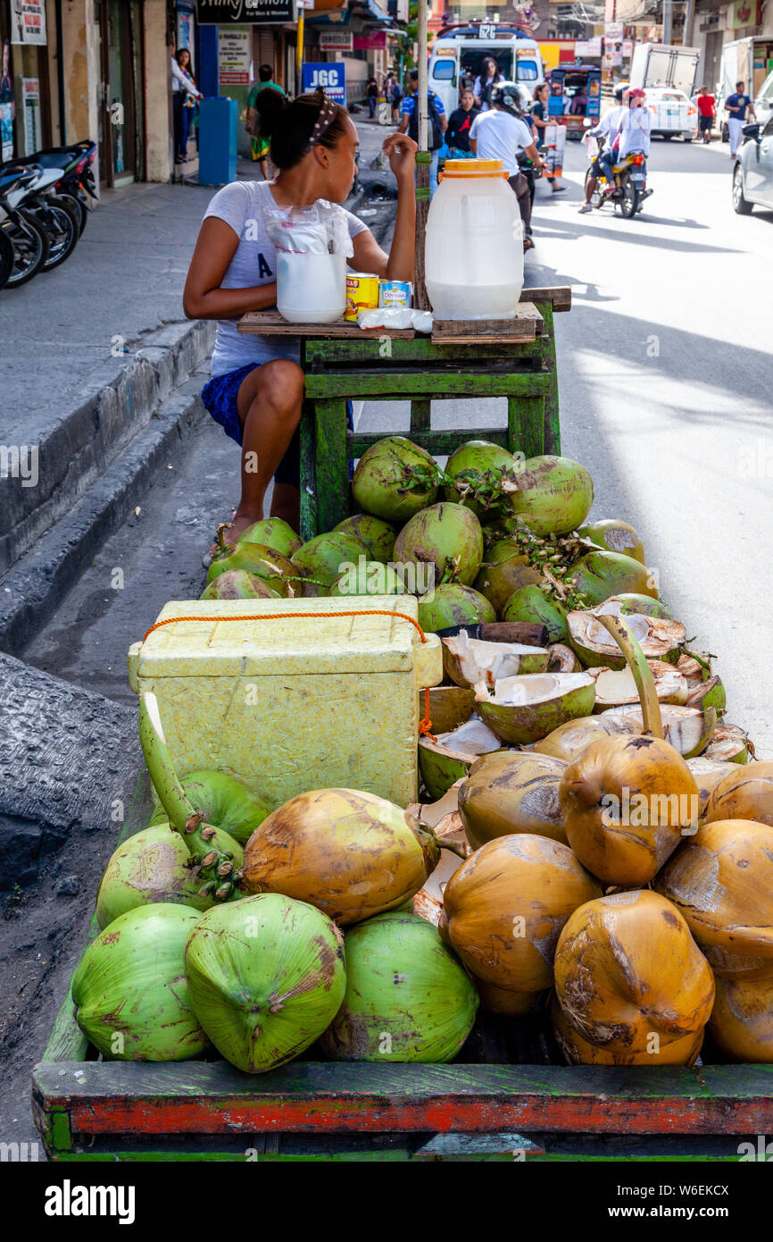 Una giovane donna filippina e succo di Buko (una acqua di cocco drink) stallo, Cebu City Cebu, Filippine Foto Stock