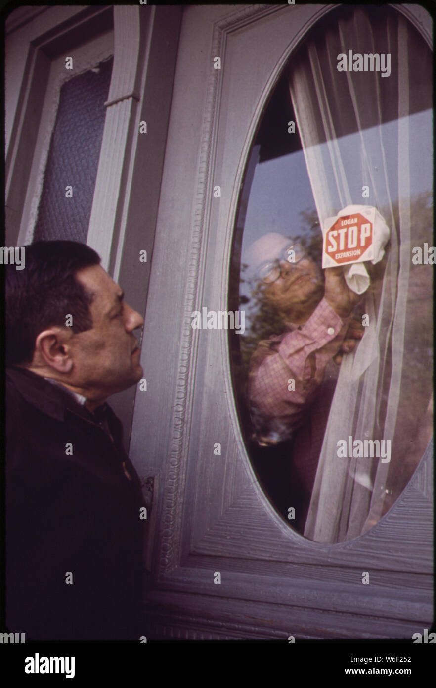 Antonio Bruno appone un adesivo di protesta davanti alla porta di casa del suo NETTUNO CASA DI STRADA MENTRE GIUSEPPE PORZIO guarda a. Il sig. BRUNO, che insegna Diritto ed economia a RINDGE TECHNICAL HIGH SCHOOL DI CAMBRIDGE, È UN LEADER NELLA COMUNITÀ EUROPEA. Il sig. PORZIO, un vicino, è CO-PRESIDENTE DEL COMITATO PER LA LEGISLAZIONE DELLA EAST BOSTON consiglio di quartiere. Problemi ambientali ed economici causati da adiacente l'Aeroporto di Logan sono di primaria importanza sia per gli uomini Foto Stock