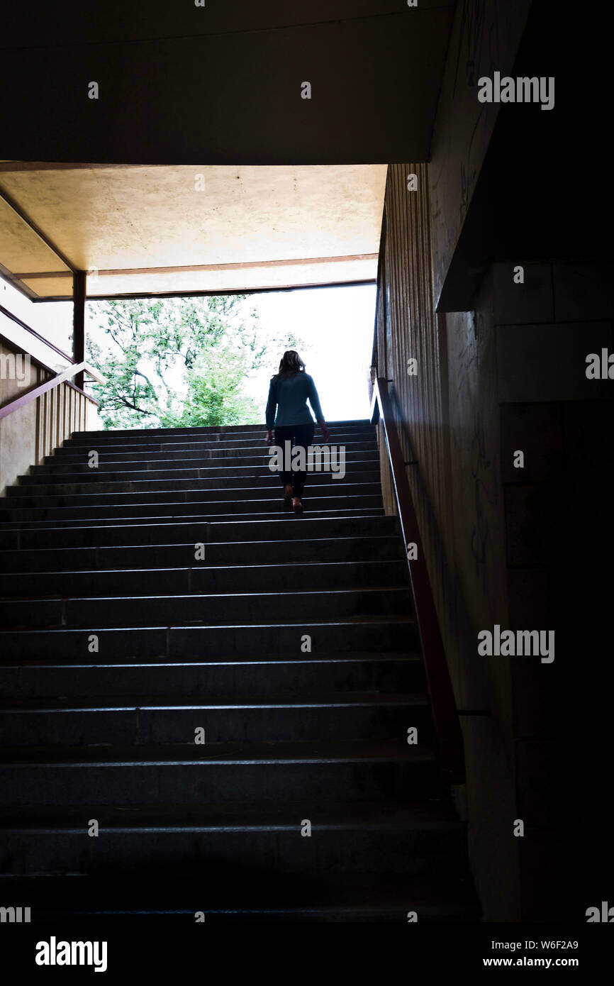 Moody immagine di una donna che cammina al piano di sopra al di fuori di un sottopassaggio Foto Stock