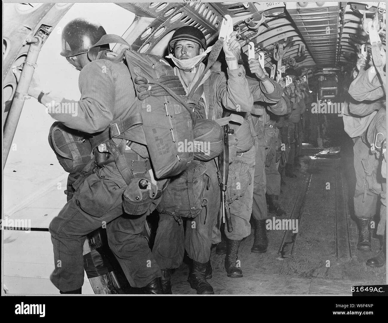 Attorno al punto in aria sottile, un paracadutista della 187th Regimental Combat Team sospende momentaneamente durante l'uomo di seguito cancella l'area; la portata e il contenuto: circa al passo in aria sottile, un paracadutista della 187th Regimental Combat Team sospende momentaneamente durante l'uomo di seguito cancella l'area. Questa è una pratica parachute jump in cui 1.000 troopers, completamente armati per combattere, in primo luogo sono stati trasportati negli Stati Uniti Estremo Oriente le forze di aria C-54 Skymasters ad un rendezvous point, trasferiti in C-46 Commandos e volato al presente nella zona di caduta. 315Air Division (combattimento) Cargo trasporta hanno portato il 18 Foto Stock