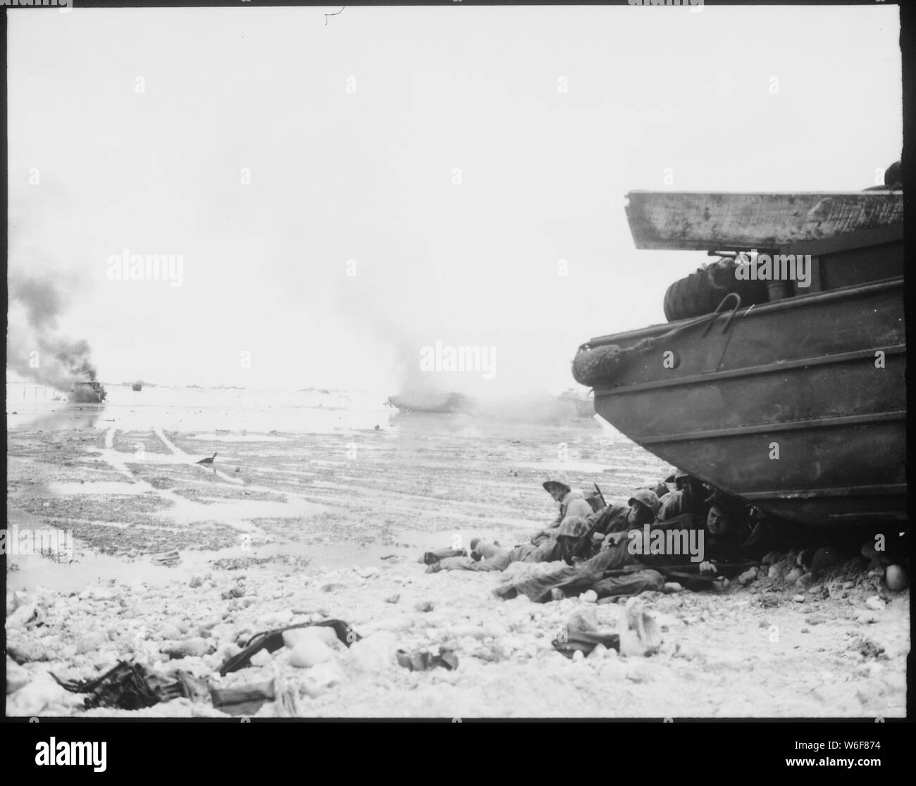 Un trattore anfibio ustioni sulla spiaggia come Marines rifugiarsi sotto un'anatra. Peleliu, settembre 1944.; Note Generali: Utilizzo di guerra e di conflitto numero 1178 quando si ordina una riproduzione o la richiesta di informazioni su questa immagine. Foto Stock