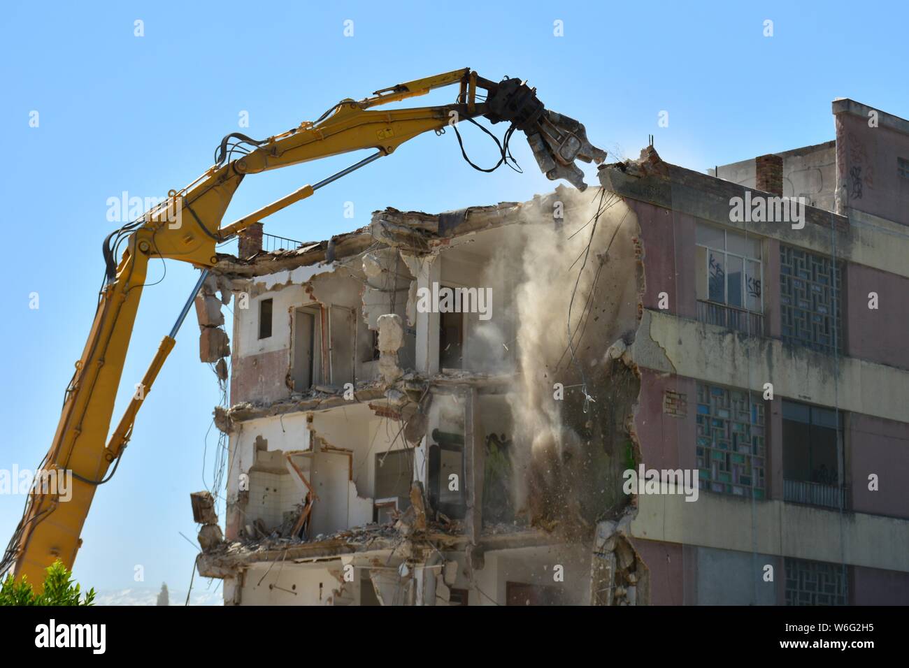 Gran máquina demoliendo onu viejo edificio de apartamentos Foto Stock