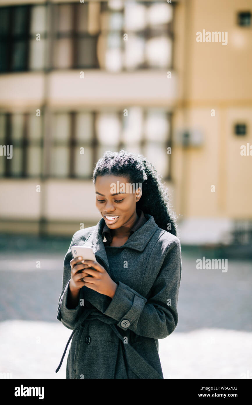 Giovane bella donna africana utilizzare il telefono in strada Foto Stock