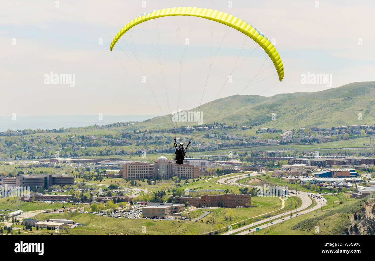 Volando sopra la città - un parapendio battenti alto sopra la Highway 6 in città di Golden, con Jefferson county Government Center in background di seguito. CO, Stati Uniti d'America. Foto Stock