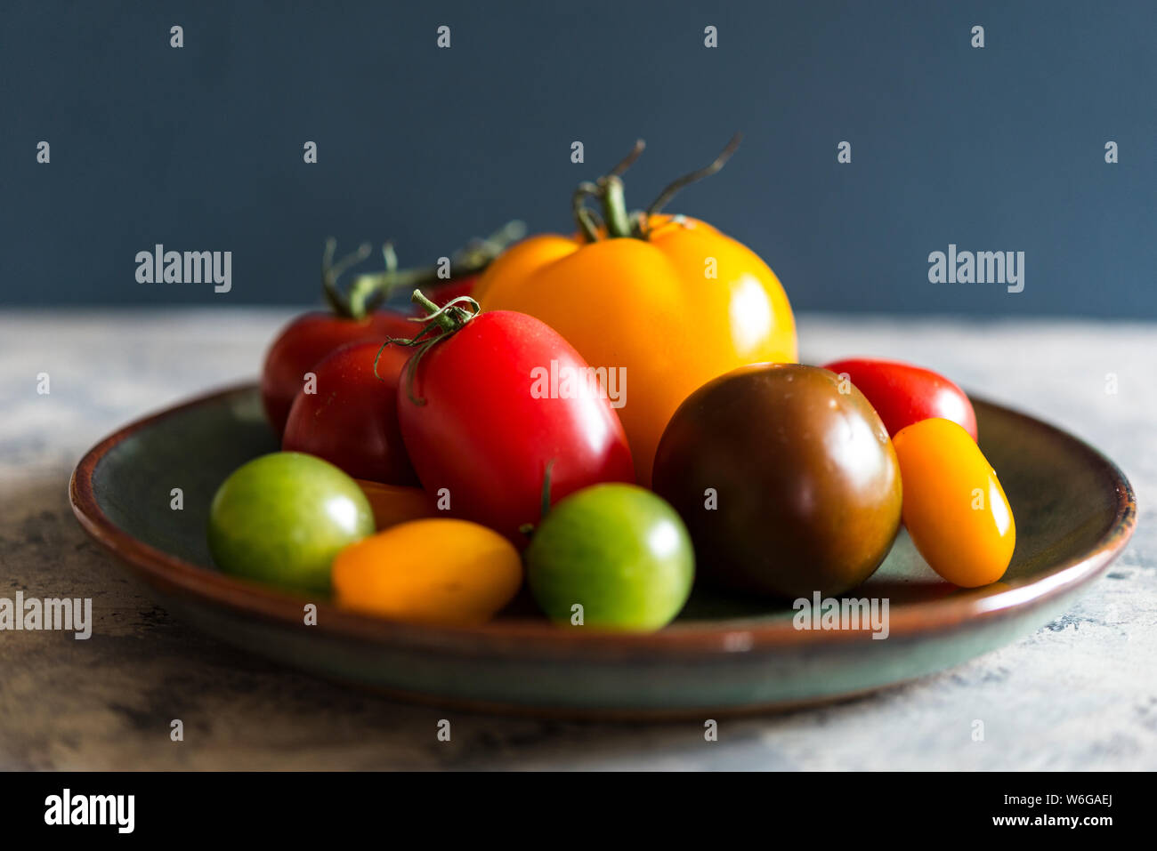 Patrimonio misto pomodori in un rustico ciotola verde Foto Stock