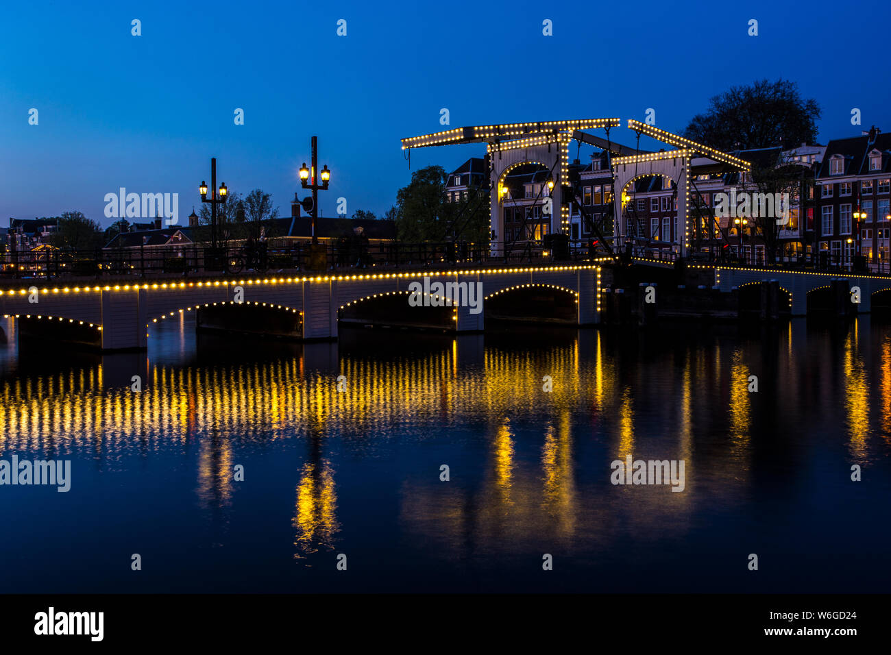 Magere Brug oltre il fiume Amstel dopo il tramonto e illuminato Foto Stock