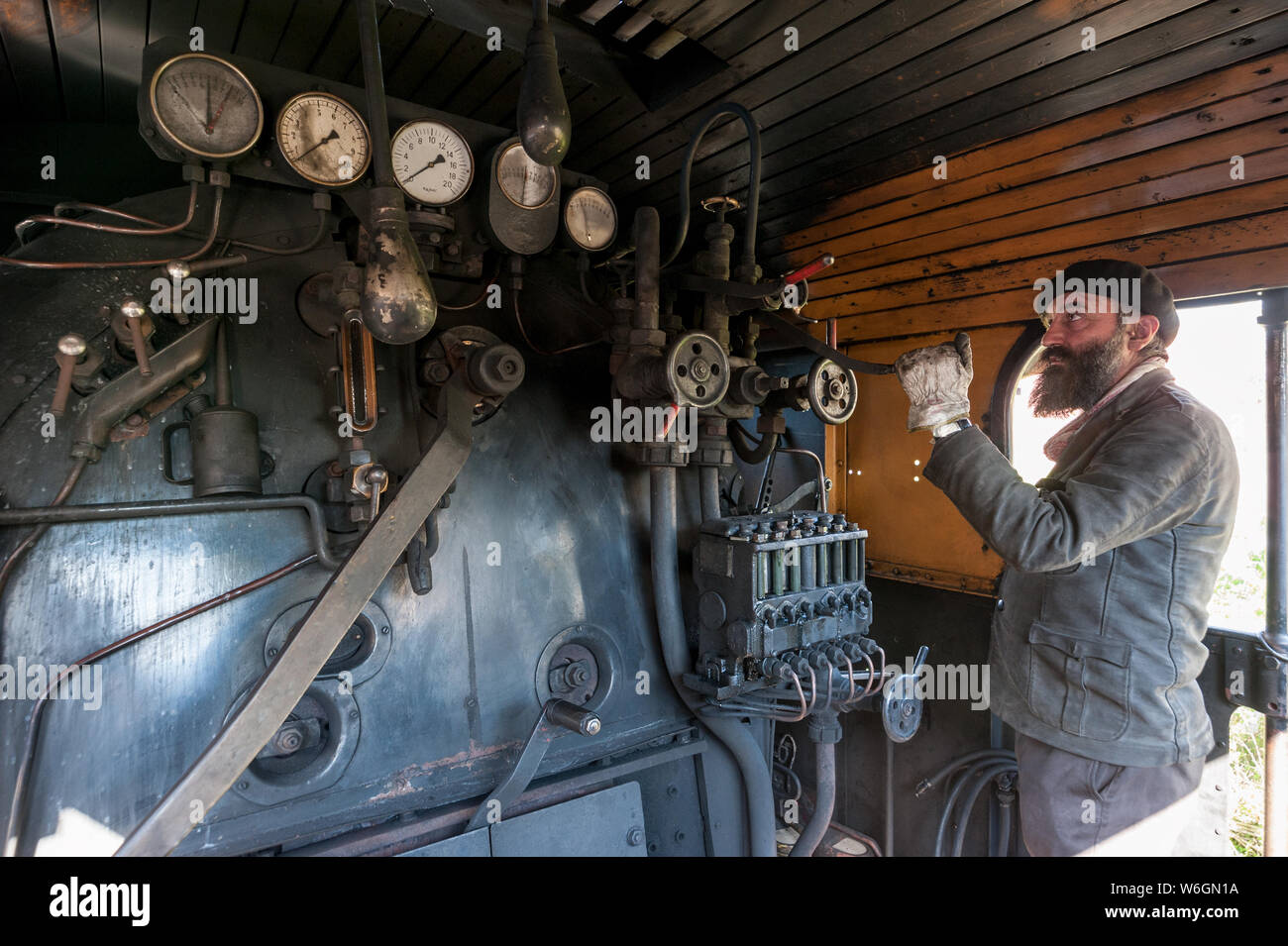 Il driver del treno vicino la locomotiva a vapore caldaia mantiene un occhio sulla pressione di vapore Foto Stock