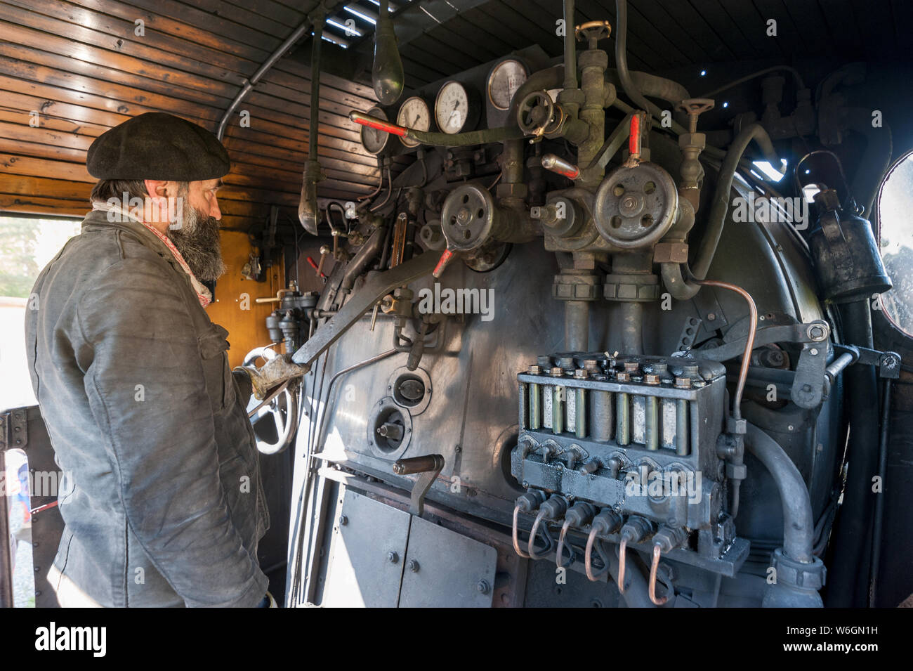 Il driver del treno vicino la locomotiva a vapore caldaia mantiene un occhio sulla pressione di vapore Foto Stock