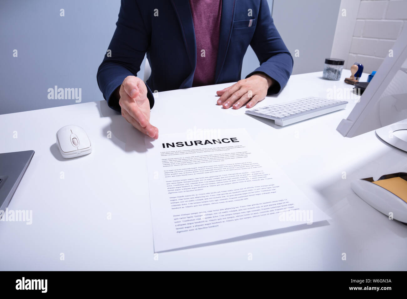 La sezione centrale di un imprenditore che mostra il documento di assicurazione su bianco scrivania in ufficio Foto Stock
