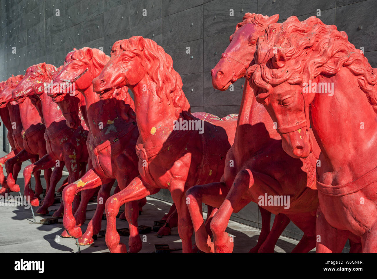 Cavalli rossi sculture, in fila, su pietre grigie sullo sfondo della parete. Foto Stock