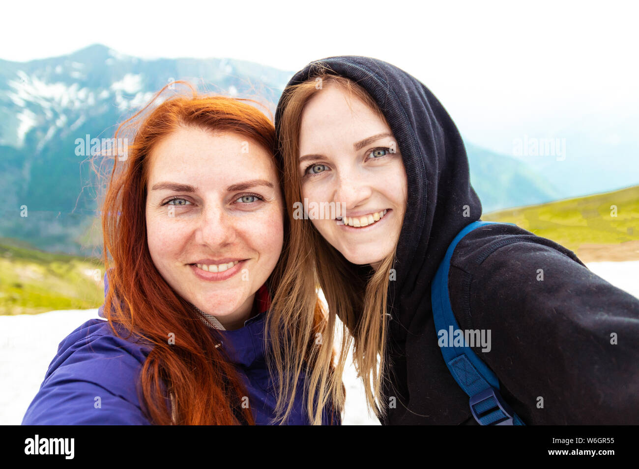 Tempo Selfie. Due ragazze di scattare una foto con il loro cellulare. Due amici godere la natura e la vita all'aperto sul lato della montagna Foto Stock