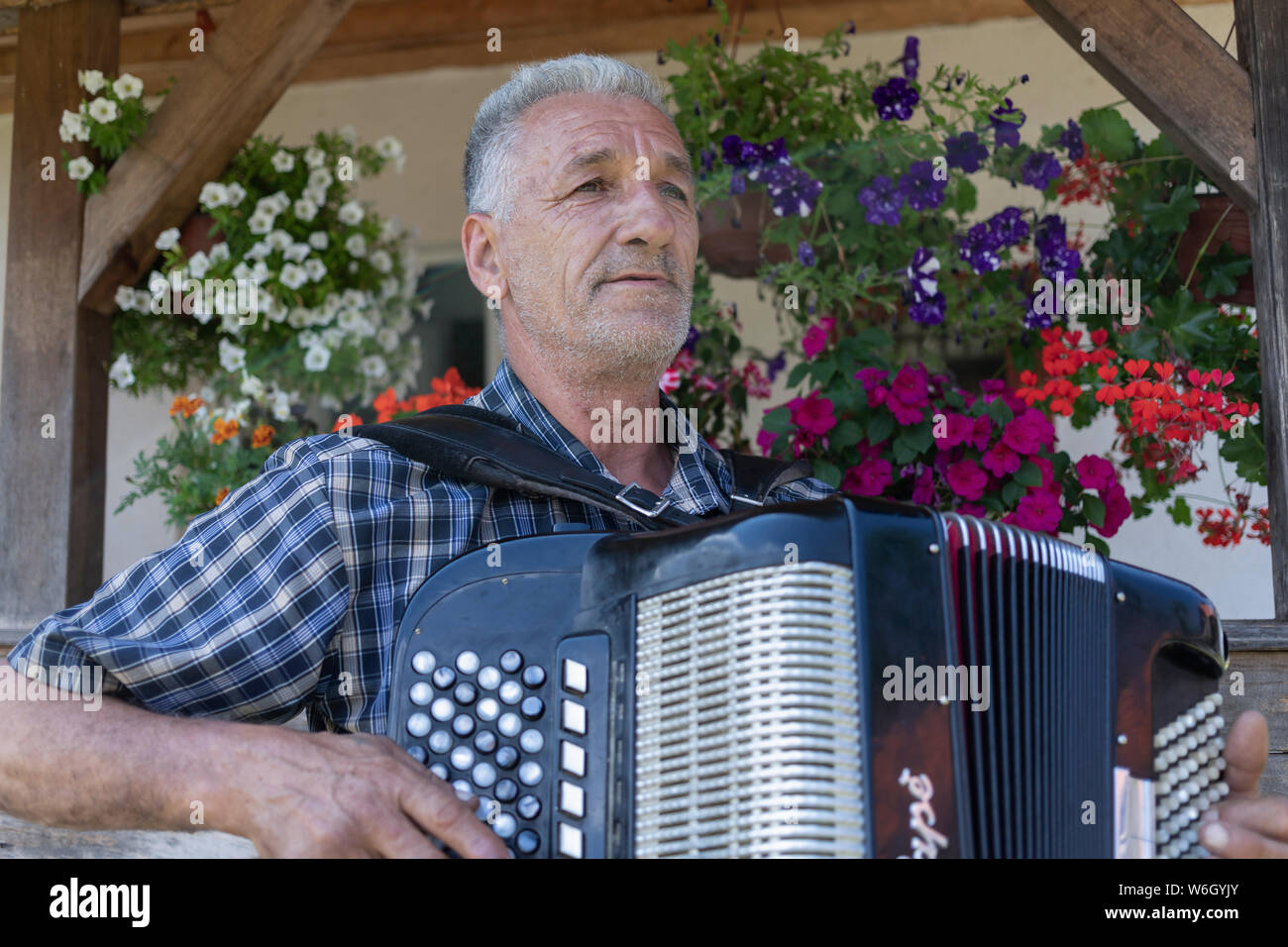 La Serbia, 20 Luglio 2019: Ritratto di un uomo locale giocando harmonica davanti a casa sua nel villaggio Solotuša Foto Stock