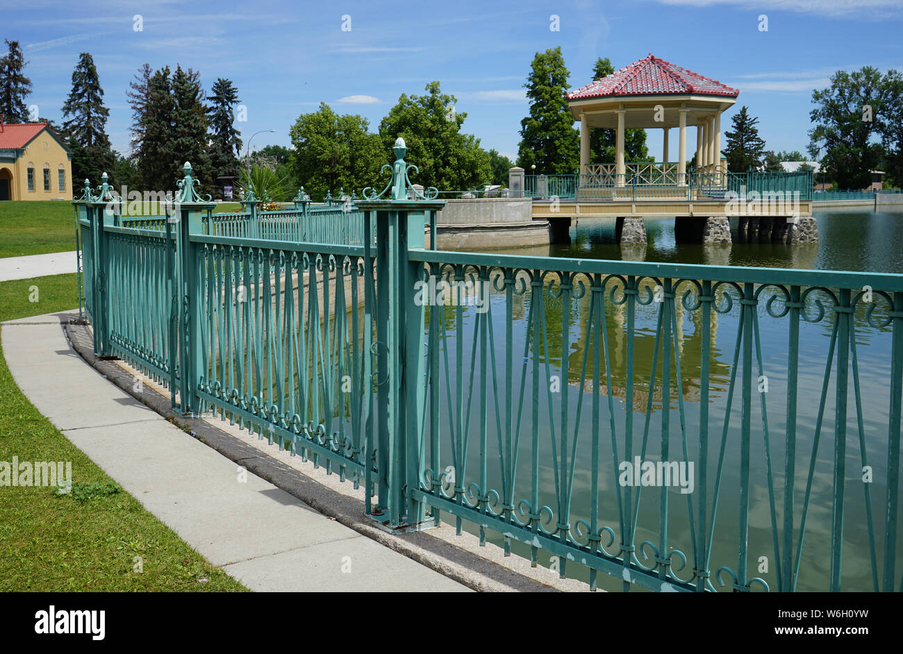 Un ornato di recinzione metallica circonda il lago Ferril a Denver parco della città. Mediante la recinzione è un marciapiede in calcestruzzo. Foto Stock