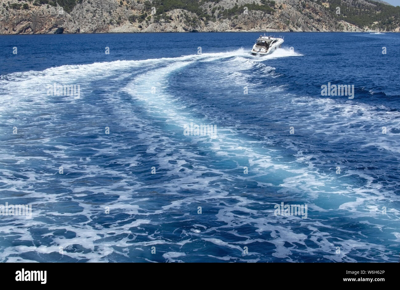 Imbarcazione a motore accelerando rendendo le onde spumeggianti in blu mediterraneo acqua su una soleggiata giornata estiva a Mallorca, Spagna. Foto Stock