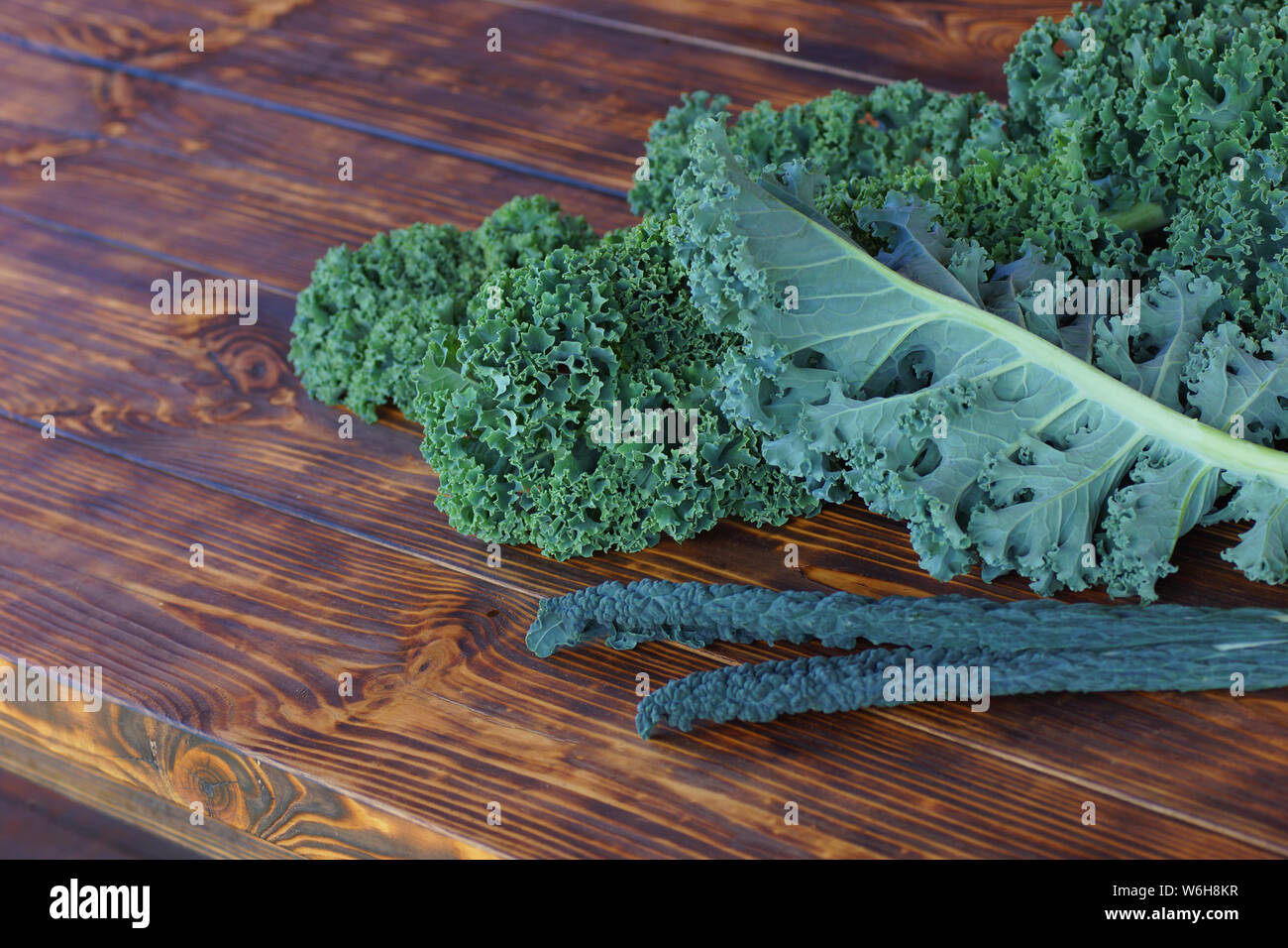 Popolari varietà di cavolo riccio, blu arricciato Vates Kale fine Tuscan kale. Succosa fresche foglie di cavolo verza giacciono su di un tavolo di legno. Foto Stock