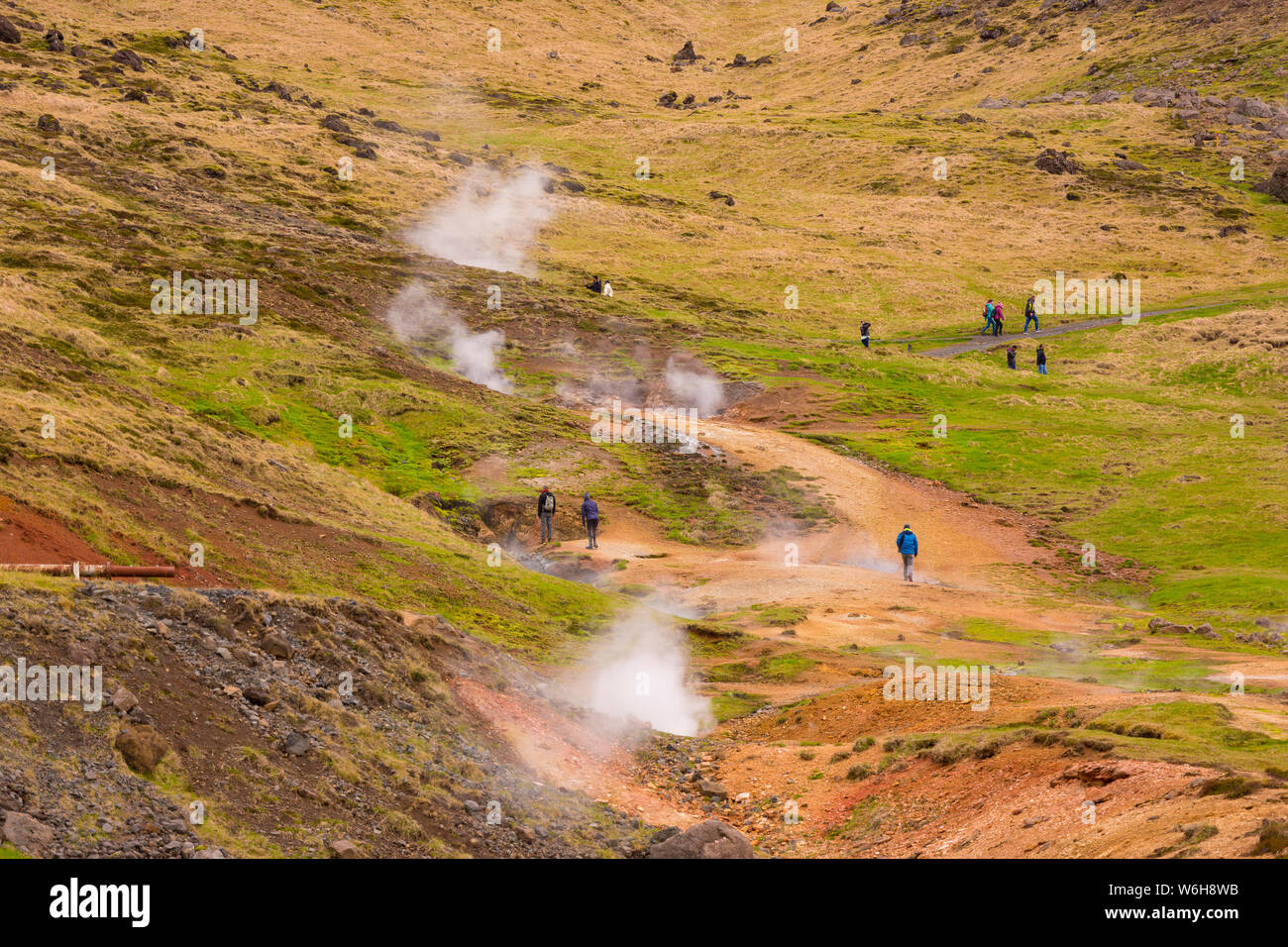 REYKJADALUR, Islanda - Visitatori escursione sul sentiero attraverso il paesaggio geotermica. Foto Stock