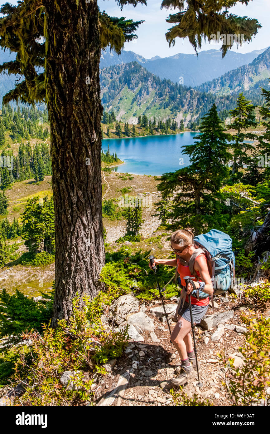 Femmina su backpacker alta Divide Trail con vista del lago pranzo in estate, Sette Laghi Bacino, il Parco Nazionale di Olympic, Montagne Olimpiche Foto Stock