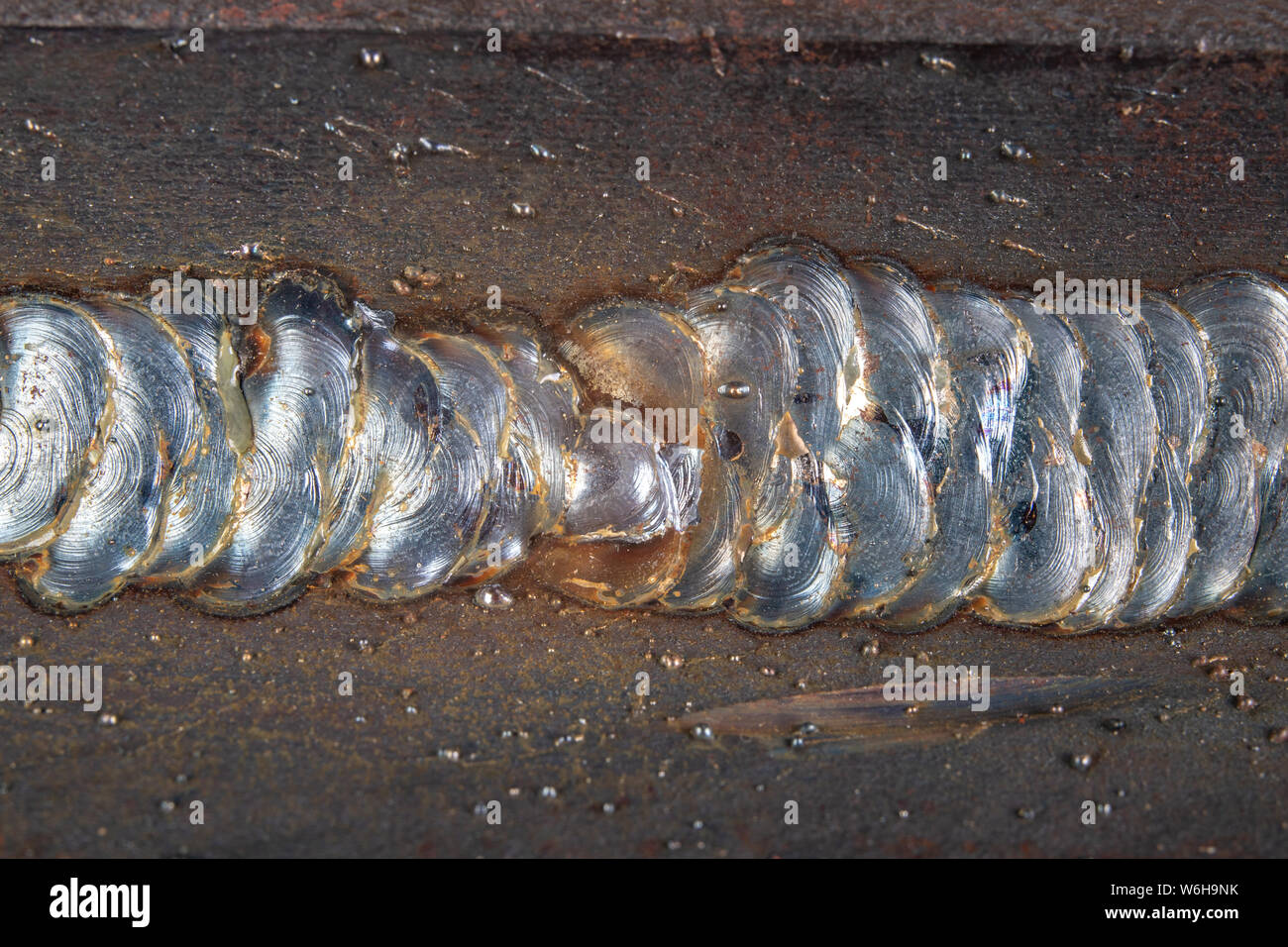 Il filetto saldatura viene effettuata utilizzando il metodo MAG. Errori nelle connessioni di acciaio mediante saldatura ad arco. Sfondo scuro. Foto Stock