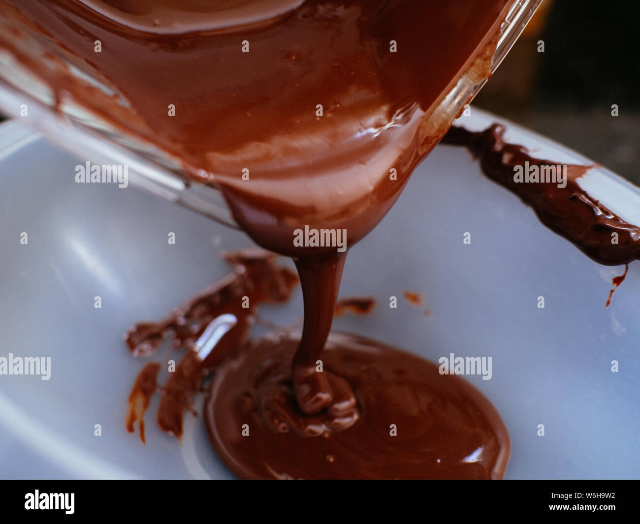 Liquido di cioccolato fuso essendo sceso su di uno stampo per vegan uova di pasqua Foto Stock