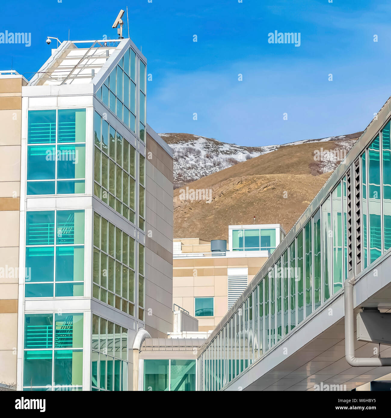 Ponte sopraelevato collegato ad un edificio moderno con la montagna e cielo blu sullo sfondo Foto Stock