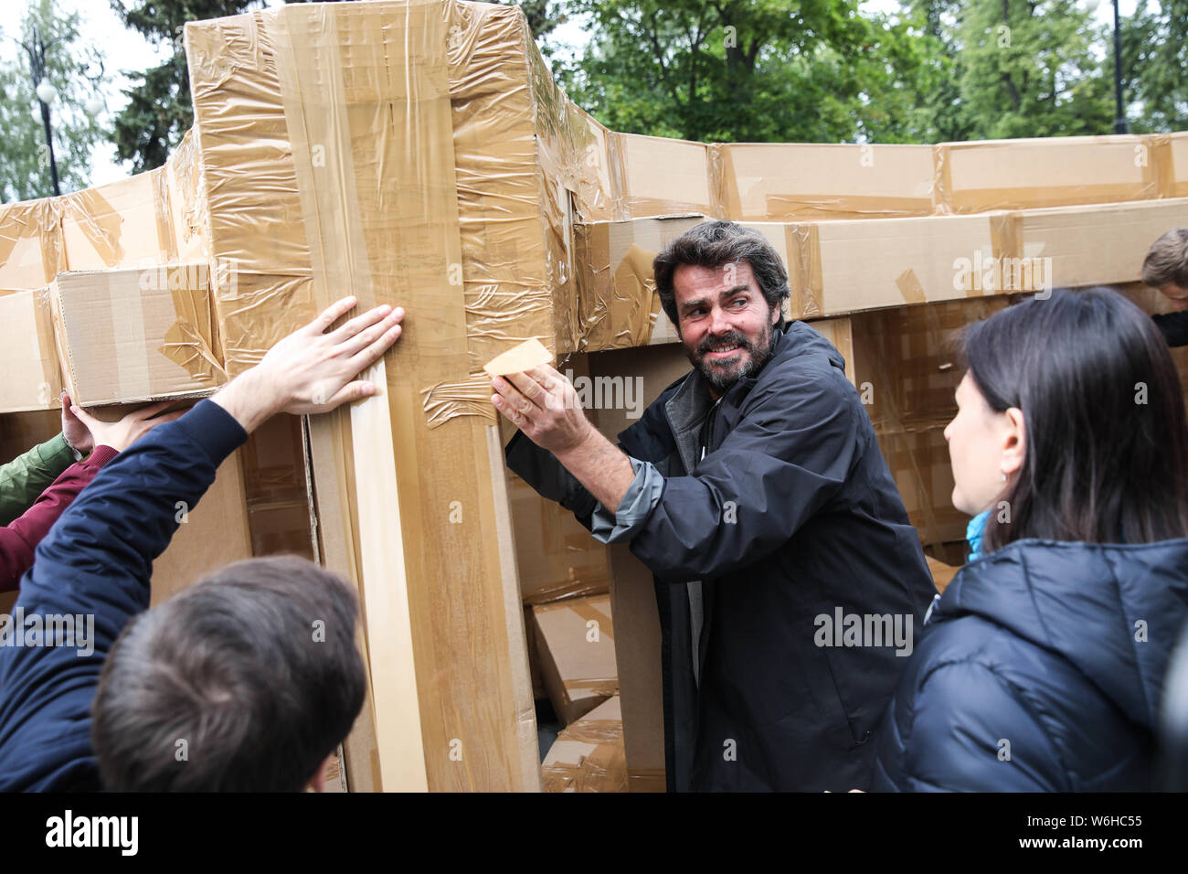 (190801) -- Mosca, 1 Agosto, 2019 (Xinhua) -- artista Olivier Grossetete (C) funziona su un ponte di cartone e nastro adesivo condotto nel parco Kuskovo a Mosca, in Russia, il 1 agosto, 2019. Una 18-metro-long flying bridge di cartone e nastro adesivo è stato assemblato ed installato nel parco Kuskovo di Mosca il giovedì. Il ponte è stato sollevato in aria con l'aiuto di tre palloni riempiti con elio. (Foto di Maxim Chernavsky/Xinhua) Foto Stock