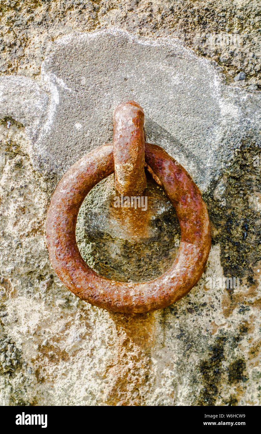 Acciaio arrugginito ormeggio anello attaccato al cemento sulla parete di roccia. Foto Stock