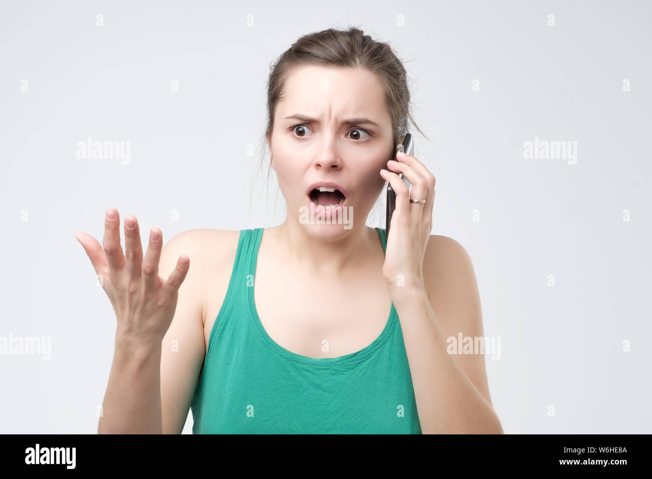 La donna lamenta mentre parla sullo smartphone, confuso e perplesso espressione. Foto Stock