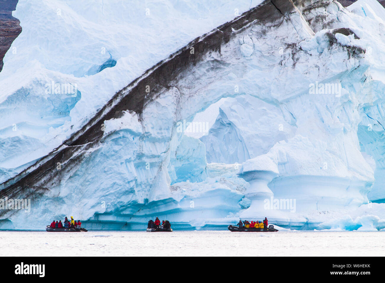 Tre Zodiacs esplorare le cuciture esuberante, pilastri, windows e scaffali ad ghiaccio progettato dal mare, in FØnfjord, Groenlandia orientale Foto Stock