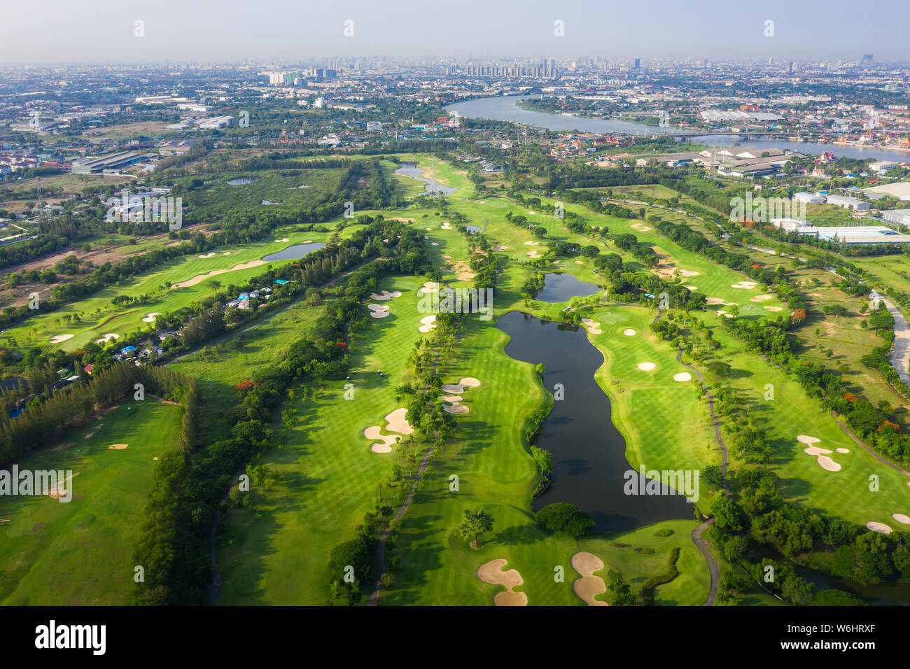 Antenna vista panoramica drone shot del bellissimo campo da golf con persone che giocano a golf nel campo e case in città. Foto Stock