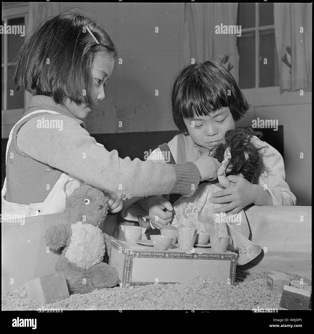 Girolamo Relocation Center, Denson, Arkansas. Giocando nel contenitore di sabbia al centro di Girolamo di pre-scuola . . .; Portata e contenuto: tutta la didascalia per questa fotografia si legge: Jerome Relocation Center, Denson, Arkansas. Giocando nel contenitore di sabbia al centro di Girolamo di pre-scuola, Giugno Fukute gioca come ella è alimentazione di Nancy Krayama la bambola. Le ragazze e i loro genitori risiedono presso il centro di Girolamo, dove costa ovest persone di ascendenza giapponese sono stati temporaneamente trova. Foto Stock