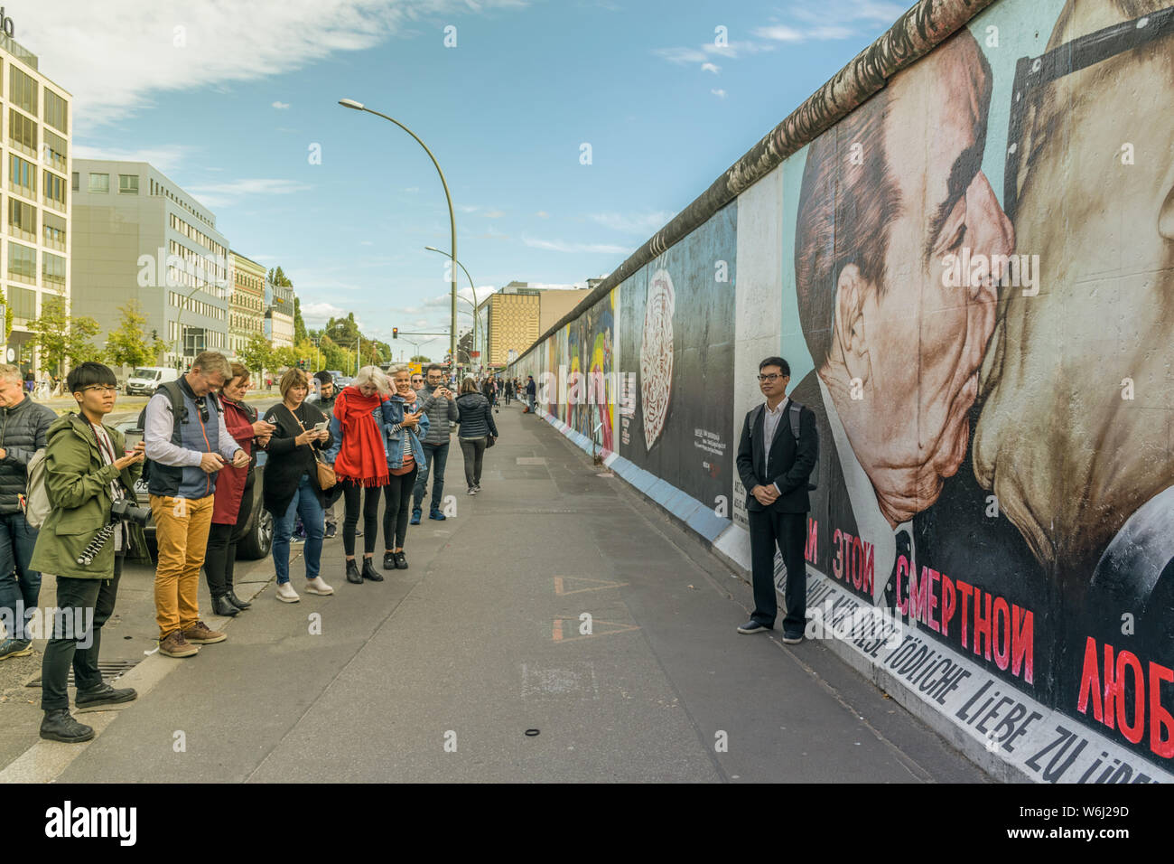 Berlino, Germania - 26 Settembre 2018: Turistica uomo asiatico di scattare una foto sul marciapiede vicino al 'Il Bacio della morte" dipinto sul muro di Berlino a Foto Stock