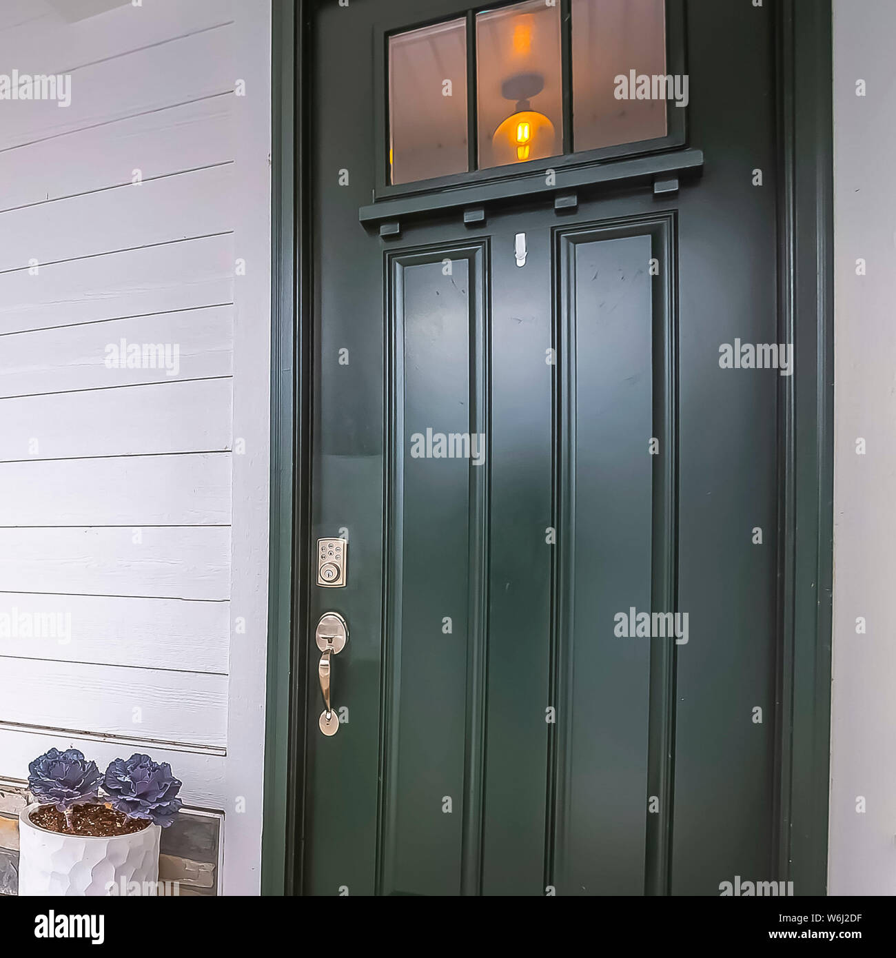 Home quadrato con facciata vetrata di vetro porta anteriore e arredamento sul portico di calcestruzzo Foto Stock