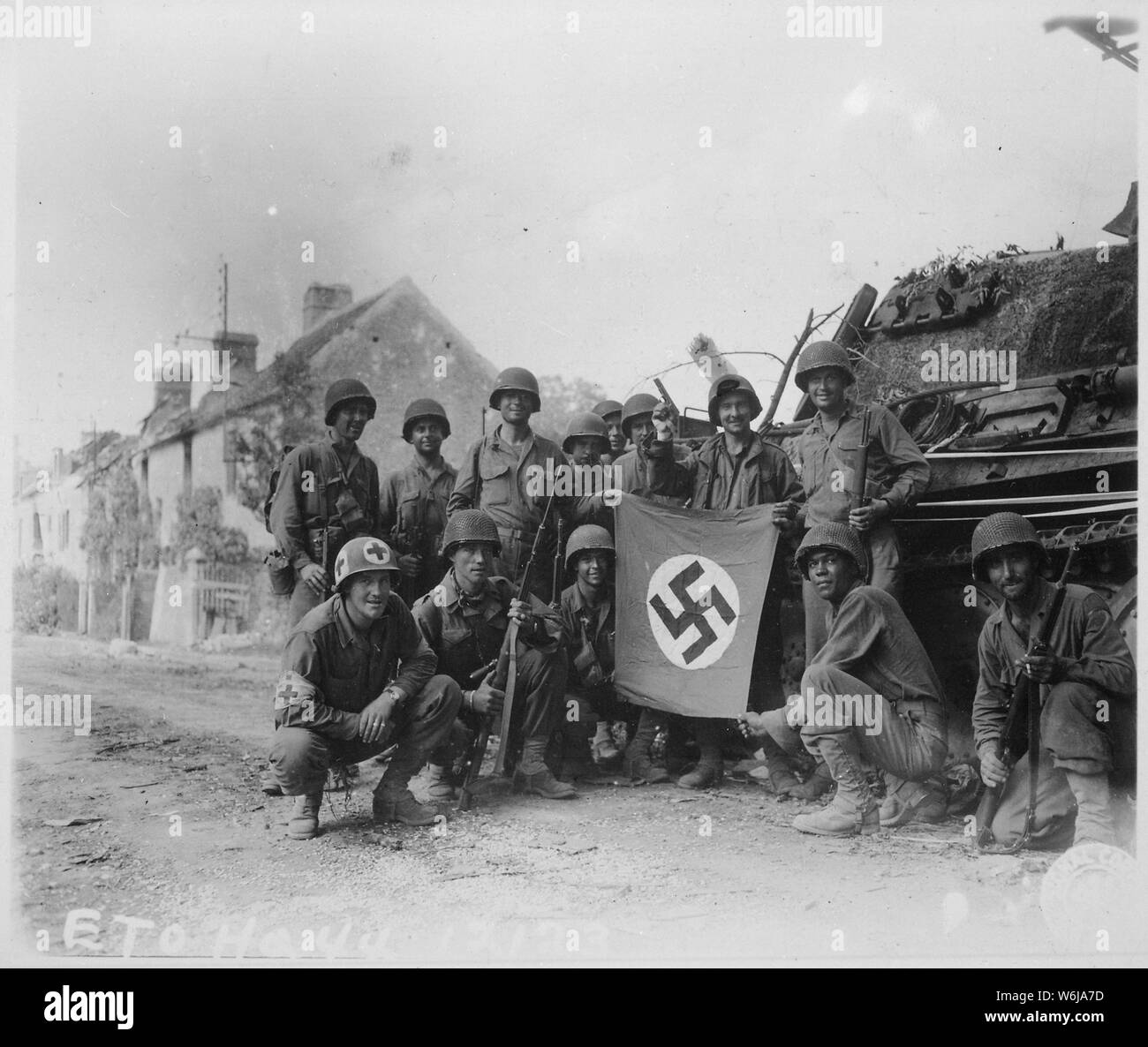 Allineate di fronte del relitto di una vasca di tedesco e la visualizzazione di un catturato swastika, è un gruppo di Yank fanti che erano rimasti dietro al mop in Chambois, Francia, ultima roccaforte dei nazisti in La Falaise Gap area.; Note Generali: Utilizzo di guerra e di conflitto numero 1049 quando si ordina una riproduzione o la richiesta di informazioni su questa immagine. Foto Stock