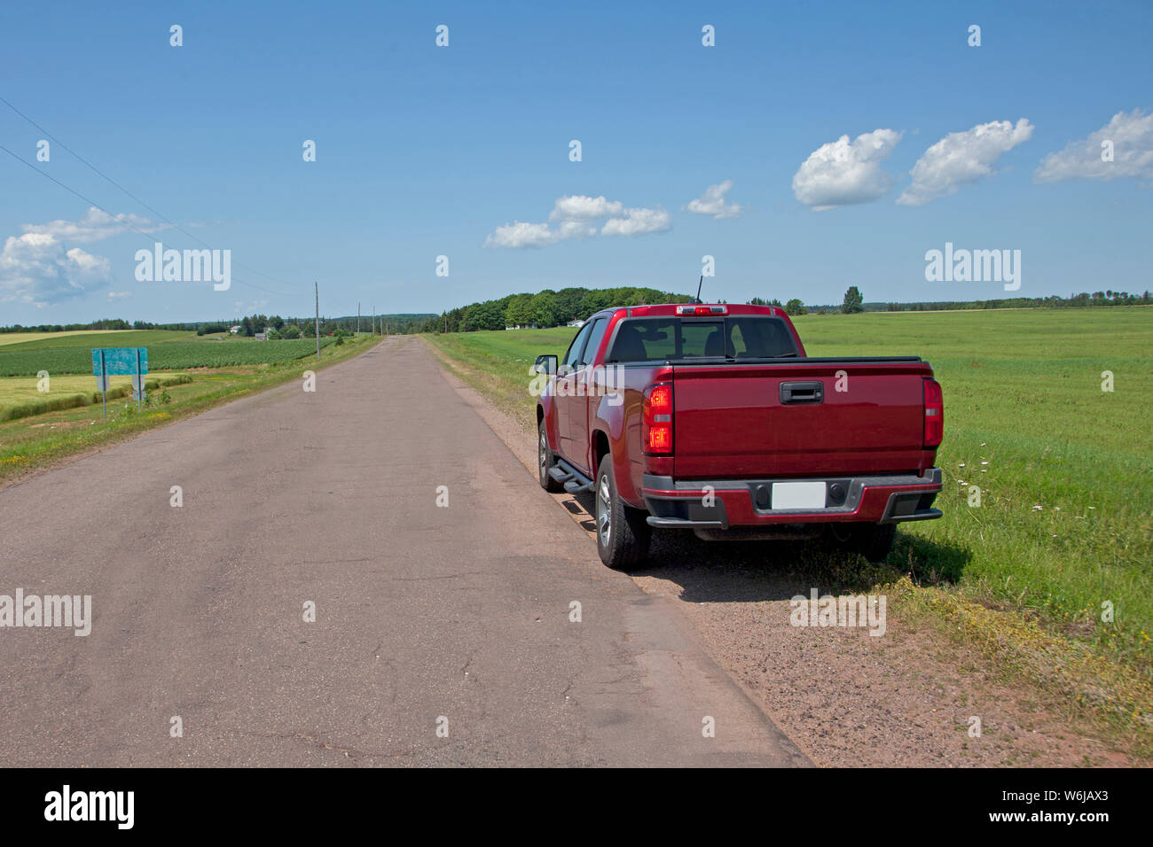 Red pickup truck parcheggiato su una strada rurale in attesa di aiuti per il salvataggio o per iniziare il viaggio in estate Foto Stock