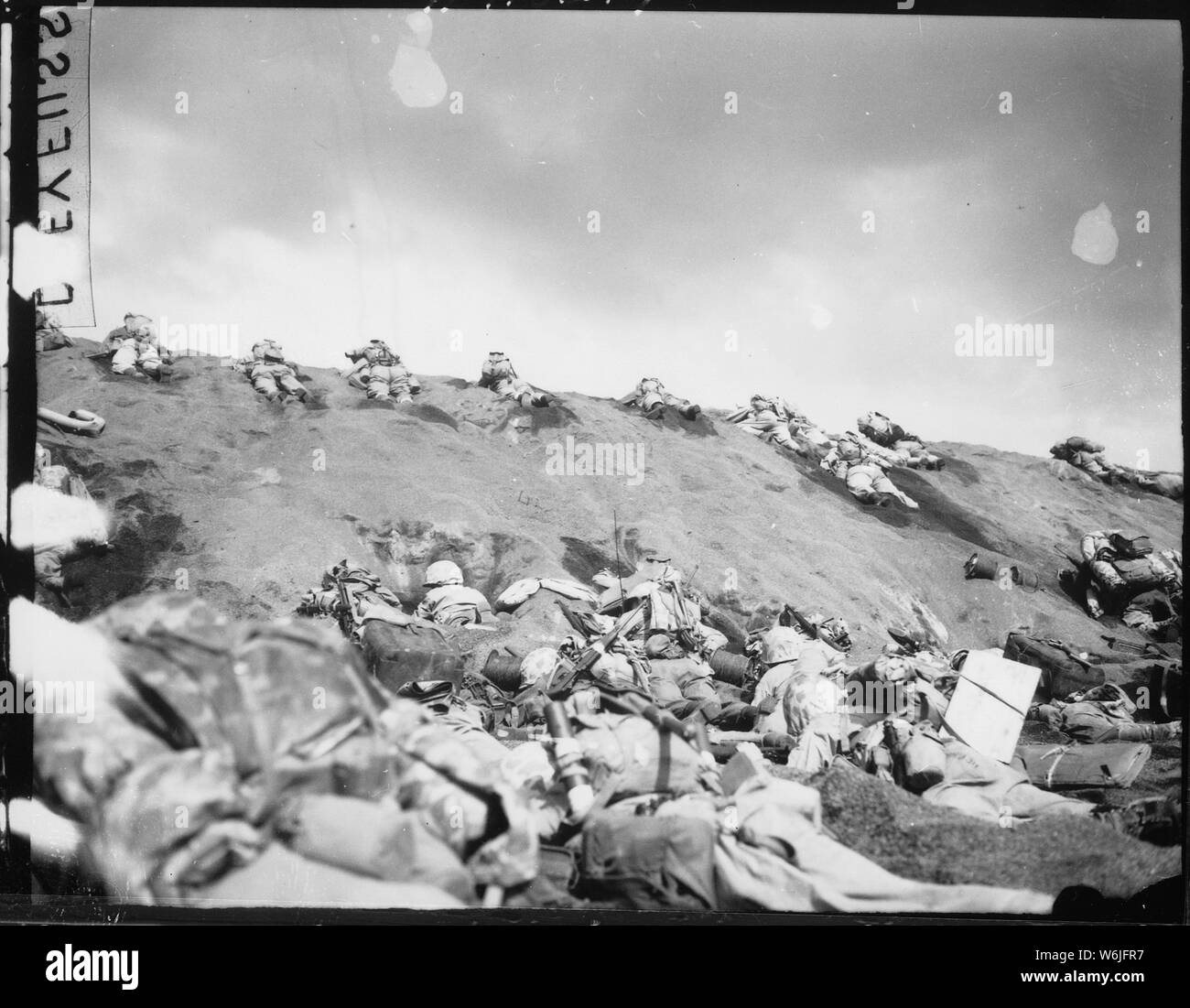 Marines della quinta Divisione pollice il loro modo su un pendio in Red Beach No. 1 verso Surbachi Yama come il fumo della battaglia si sposta su di loro. Iwo Jima, 19 febbraio 1945.; Note Generali: Utilizzo di guerra e di conflitto numero 1217 quando si ordina una riproduzione o la richiesta di informazioni su questa immagine. Foto Stock
