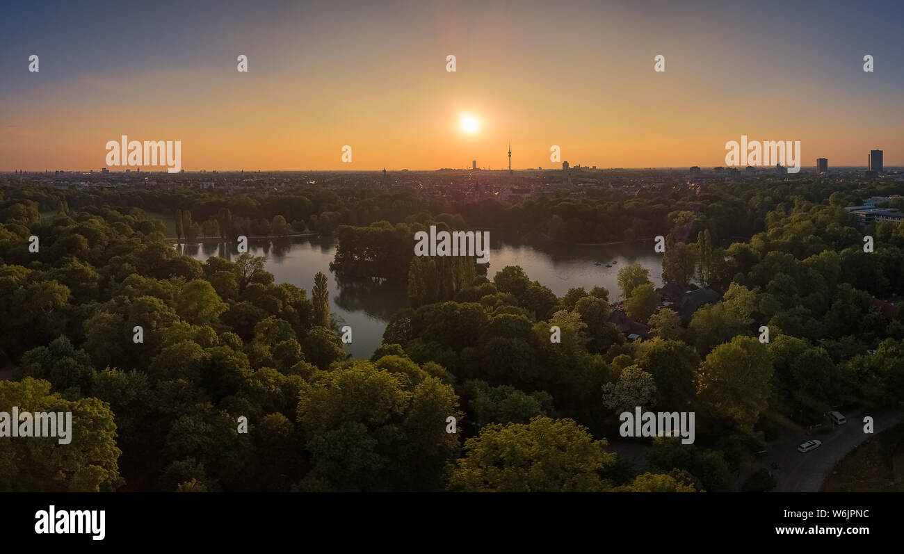 Un incredibile tramonto su un lago, circondato da alberi a Monaco, Baviera. Foto Stock