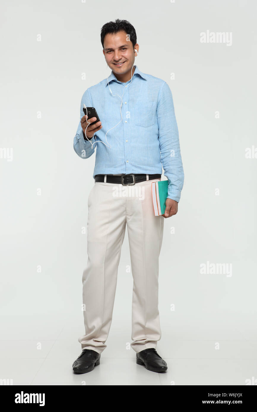 College boy ascoltare musica con un telefono cellulare e. sorridente Foto Stock