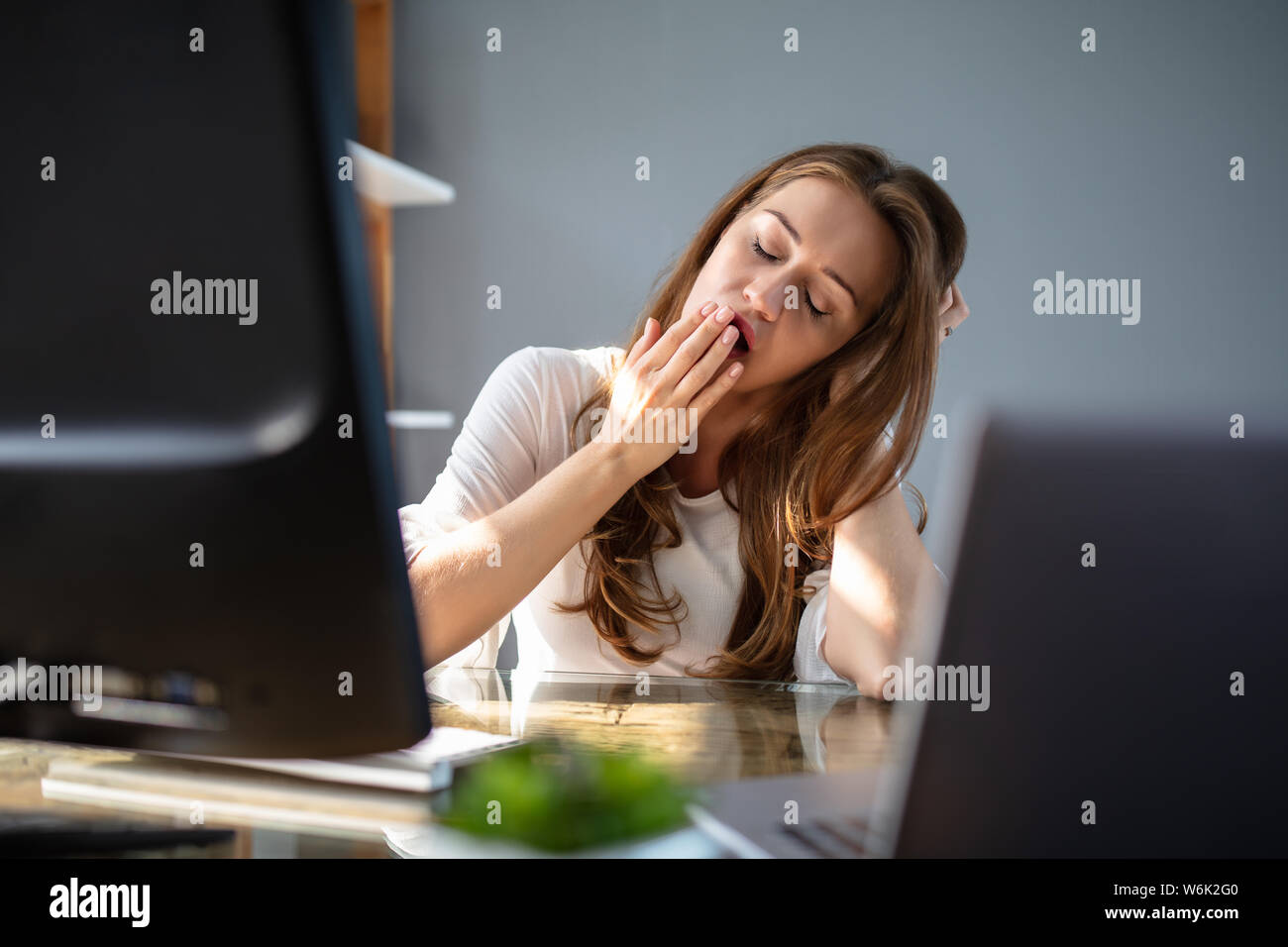 Stanco giovane imprenditrice sbadigli al suo posto di lavoro Foto Stock