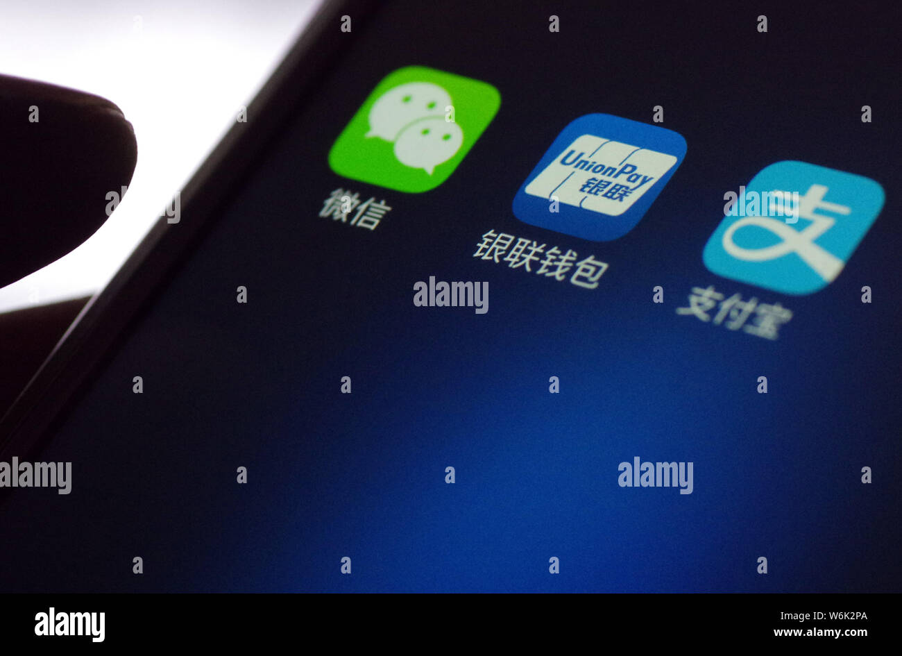 --FILE--un cinese utente del telefono mobile mostra le icone delle applicazioni mobile (da sinistra) messaging app Weixin o WeChat, di Tencent, portafoglio mobile UnionPay Foto Stock