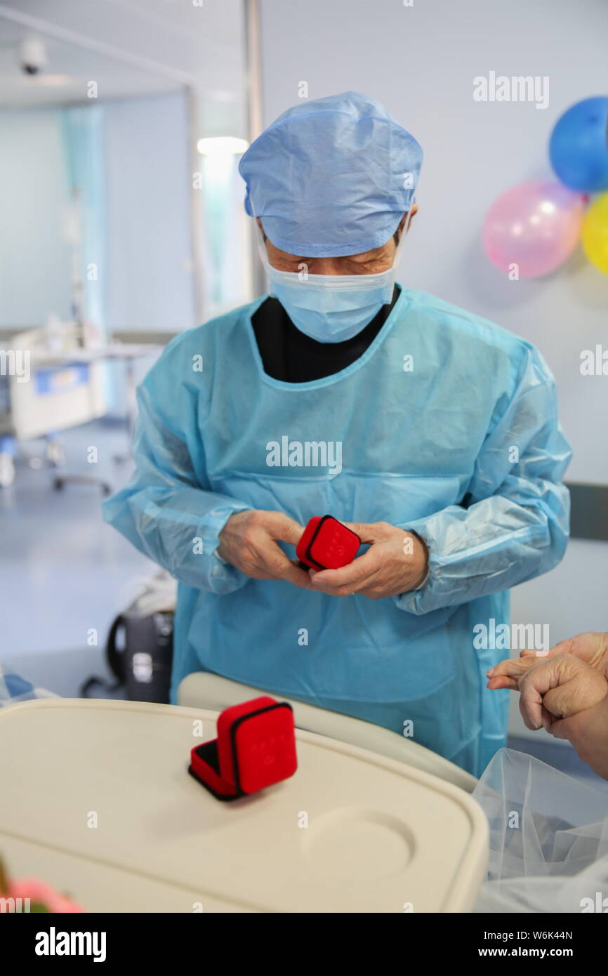 Il 79-anno-vecchio uomo cinese soprannominato Gu cerca di mettere un anello al dito del suo 75-anno-vecchio inconscio moglie soprannominato Wang durante una cerimonia per celebrare Foto Stock