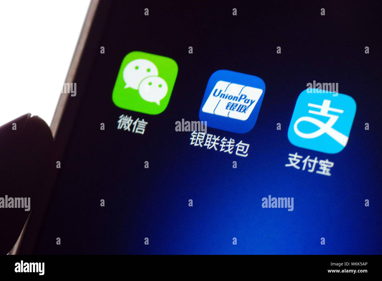 --FILE--un cinese utente del telefono mobile mostra le icone delle applicazioni mobile (da sinistra) messaging app Weixin o WeChat, di Tencent, portafoglio mobile UnionPay Foto Stock